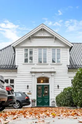 a white house with a green door and a car at Experience Norway's History I With Free Parking in Bergen