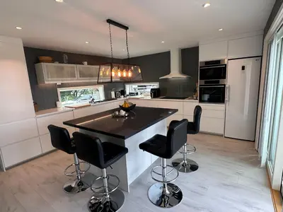 a kitchen with a island with black counter chairs at Enebolig Trondheim syd in Trondheim