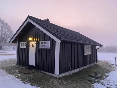 a black shed with a white door in the snow at Tørresvangen in Tynset