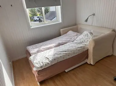 an unmade bed in a room with a window at Stor enebolig Trondheim syd in Trondheim