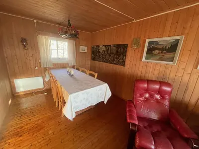 a dining room with a table and a red chair at Charming Cabin Ski-In Access And Pet Friendly in Beitostøl