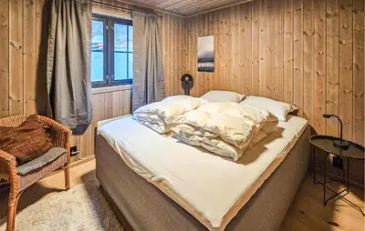 a bedroom with a bed and a chair and a window at Stunning Home In Vinje With Wifi in Trovatn