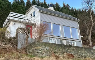 a large white house with a stone wall at Cozy Home In Nerlandsøya Grunnkrets in Kvalsvik