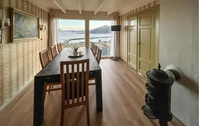 a dining room with a table and chairs and a window at Cozy Home In Nerlandsøya Grunnkrets in Kvalsvik