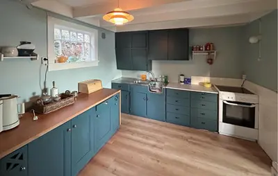 a kitchen with blue cabinets and a wooden floor at Cozy Home In Nerlandsøya Grunnkrets in Kvalsvik
