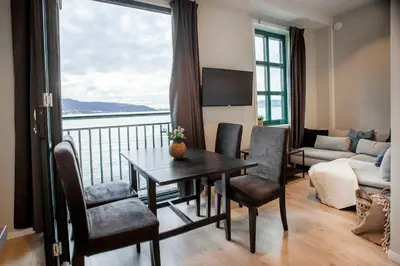 a living room with a table and chairs and a large window at Beautiful Harbour Apartment With French Balcony in Bergen