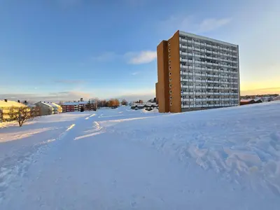a snow covered street with a building in the distance at Ski in ski out 2bdr apartment in Trondheim
