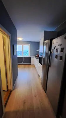 a kitchen with a refrigerator and a wooden floor at Ski in ski out 2bdr apartment in Trondheim