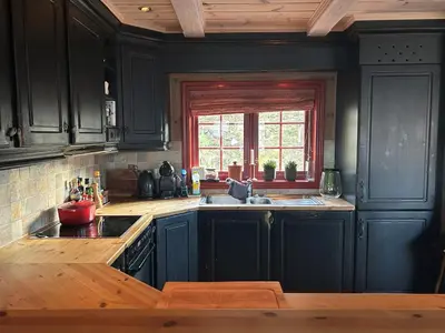 a kitchen with black cabinets and a sink and a window at Spacious cabin with beautiful Geilo views in Geilo