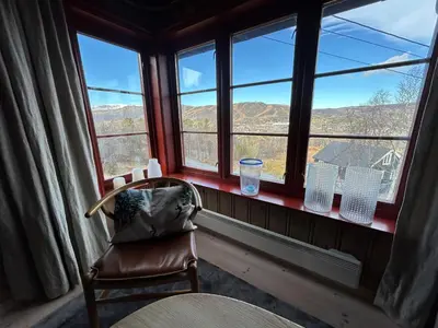 a chair sitting in front of a window with a view at Spacious cabin with beautiful Geilo views in Geilo