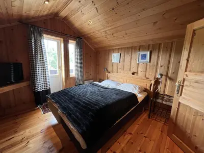 a bedroom with a bed in a room with wooden walls at Grand Log Cabin With Fireplace And 12-14 Beds in Beitostøl