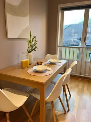 a dining room table with white chairs and a large window at Lovely 3-room gem in the heart of Bergen City in Bergen