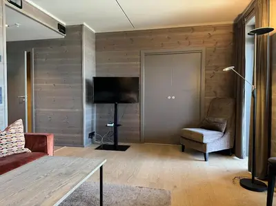 a living room with a tv and a couch and a chair at Riddertunets stilfulle in Beitostøl