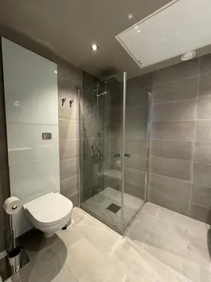a bathroom with a toilet and a glass shower at Riddertunets utsikt til Mugnetind in Beitostøl