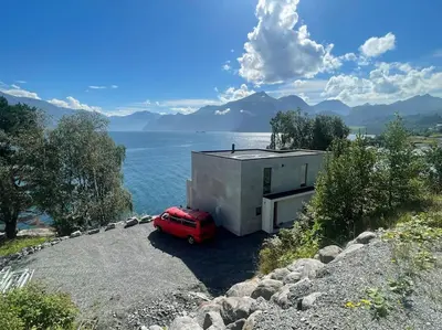 a red car parked in front of a house next to the water at Amazing View in Stranda