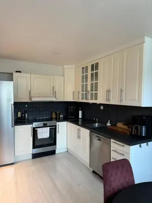 a kitchen with white cabinets and stainless steel appliances at Leilighet nært Granåsen skisenter in Trondheim
