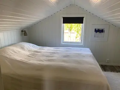 a large bed in a white room with a window at Det lille huset i Slipveien in Bud