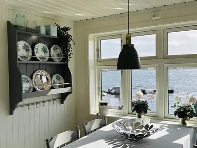 a dining room with a table and a view of the ocean at Det lille huset i Slipveien in Bud