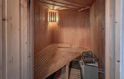 a wooden sauna with a table and a stove at Awesome Home In Lillehammer With Sauna in Lillehammer