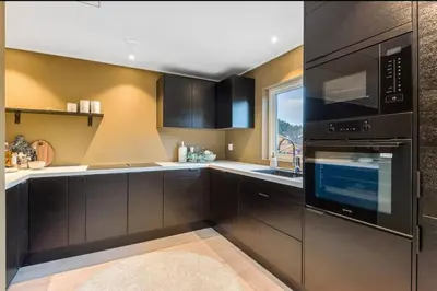 a kitchen with dark brown cabinets and a window at Flott bolig til VM! Gåavstand in Trondheim