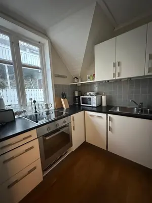 a kitchen with white cabinets and a sink at Historical house with view and separate entrance in Ålesund