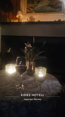 a glass of wine sitting on a table with lights at Eides Hotel in Høyanger