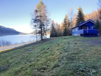 a blue house on a hill next to a lake at Koselig blått hus - utsikt Losna in Tretten