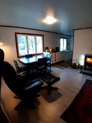 a living room with a table and chairs and a fireplace at Koselig blått hus - utsikt Losna in Tretten
