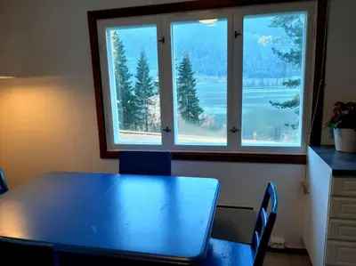 a table and chairs in a room with two windows at Koselig blått hus - utsikt Losna in Tretten