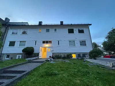 a large white building with a yellow door at Ålesund room with shared shower in Ålesund