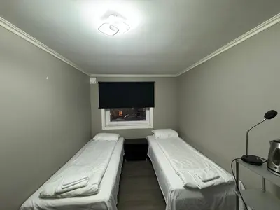 two beds in a small room with a window at Ålesund room with shared shower in Ålesund