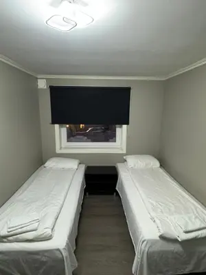 two beds in a small room with a window at Ålesund room with shared shower in Ålesund