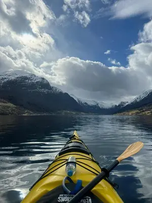 a yellow kayak on the water with a paddle at Huset Vårt - Bed and Breakfast in Hornindal