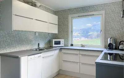 a kitchen with white cabinets and a window at 3 Bedroom Nice Home In Mjosundet in Ertvåg