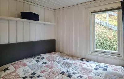 a bedroom with a quilt on a bed with a window at Amazing Home In Omastrand With Wifi in Gjuvsland