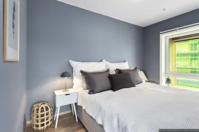a bedroom with blue walls and a bed and a window at Eksklusiv byleilighet med utsikt i Trondheim Sentrum in Trondheim