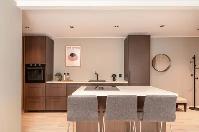 a kitchen with a kitchen island with four chairs at DINBNB Apartments l 50 meters to Bryggen l New 2023 l Sunny backyard in Bergen