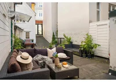 a small patio with a couch and a table at DINBNB Apartments l 50 meters to Bryggen l New 2023 l Sunny backyard in Bergen