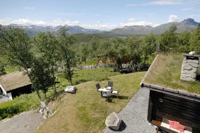 an outdoor area with a table and chairs on a hill at Charming cabin Near Jotunheimen Trails in Beitostøl