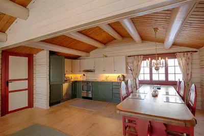 a kitchen with a wooden table and green cabinets at Charming cabin Near Jotunheimen Trails in Beitostøl