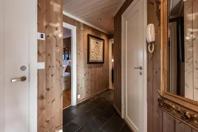 a hallway with wooden walls and a door with a mirror at Kikut Panorama Geilo Ski-in Ski-out in Geilo