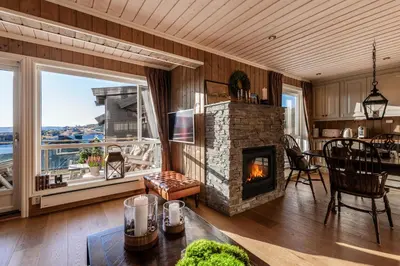 a living room with a stone fireplace and a table at Kikut Panorama Geilo Ski-in Ski-out in Geilo
