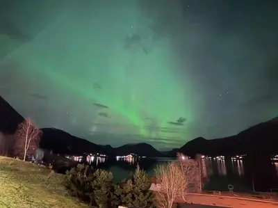 an aurora in the sky over a body of water at Idyllisk hus i Vassenden sentrum in Vassenden