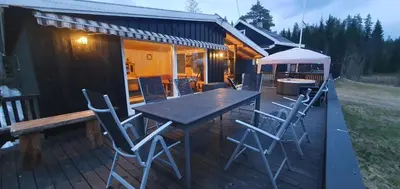 a patio with a table and chairs on a deck at Koselig feriehus med jacuzzi i Nordre Osen, kun 40 minutter fra Trysil skianlegg in Åmot