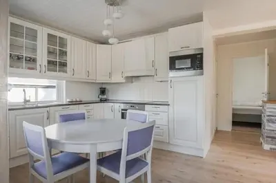 a kitchen with white cabinets and a table and chairs at Koselig feriehus med jacuzzi i Nordre Osen, kun 40 minutter fra Trysil skianlegg in Åmot