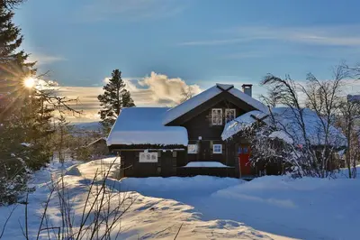 a house covered in snow with the sun behind it at Relaxing Getaway Sauna,Terrace and Pet friendly in Beitostøl