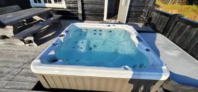 a hot tub sitting on a patio with a bench at The Whole Beautiful Cabin With Jacuzzi A Luxurious Getaway in Solberglia in Østby