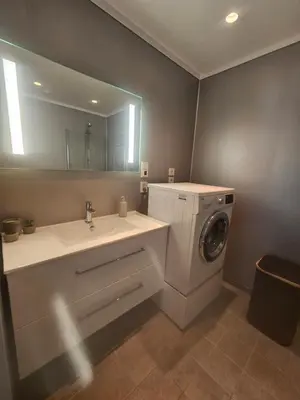 a bathroom with a sink and a washing machine at Toppleilighet på elvekanten med to romslige soverom in Førde