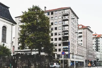 a tree in front of a large white building at Ultra central flat with balcony in Bergen