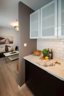a kitchen counter with white cabinets and a living room at Ultra central flat with balcony in Bergen